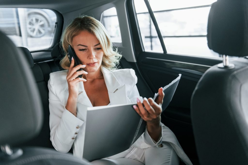 Working in the car. Woman in formal clothes is indoors in the autosalon