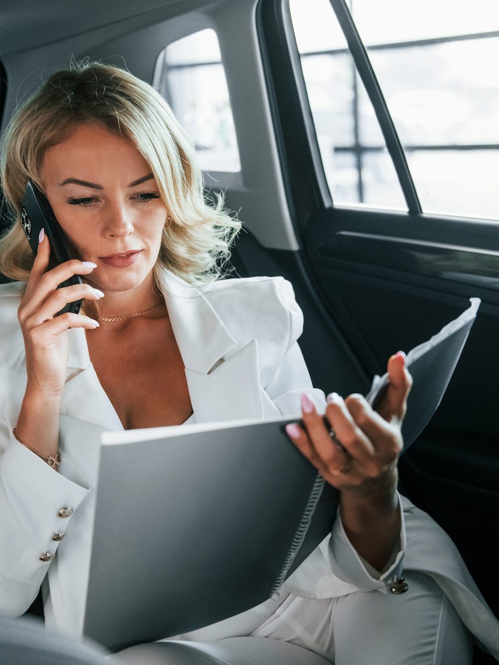 Working in the car. Woman in formal clothes is indoors in the autosalon